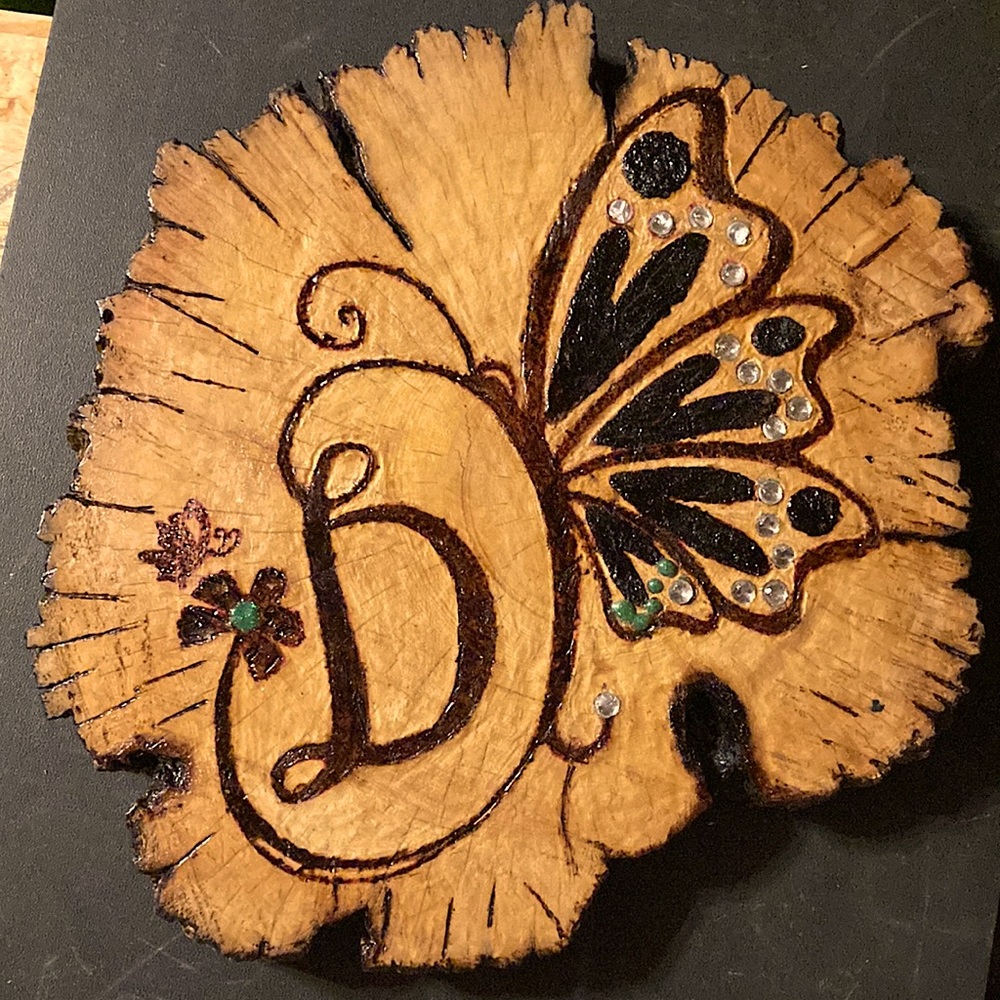 Hand made wood burned butterfly monogram D. The dark on the wings is sap. Gems